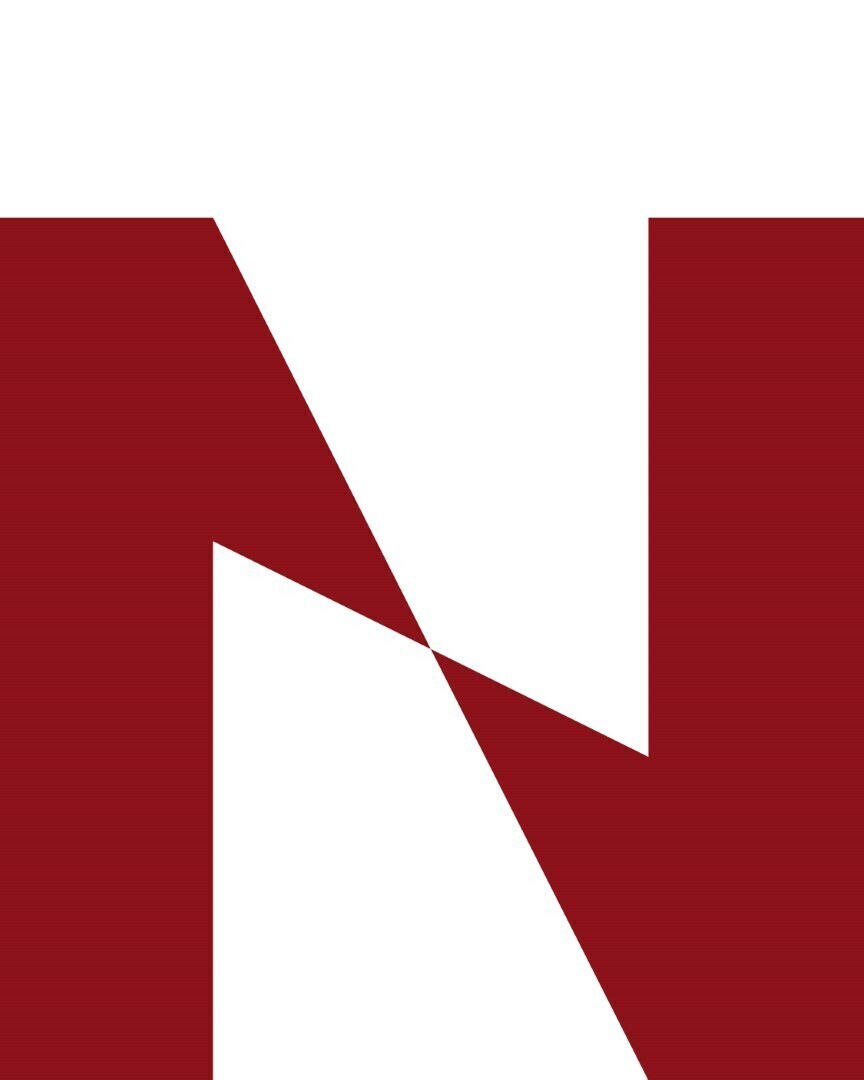 Close-up van de N van het gestileerde Nestaan-logo in rood en wit, met scherpe hoeken en geometrische vormen